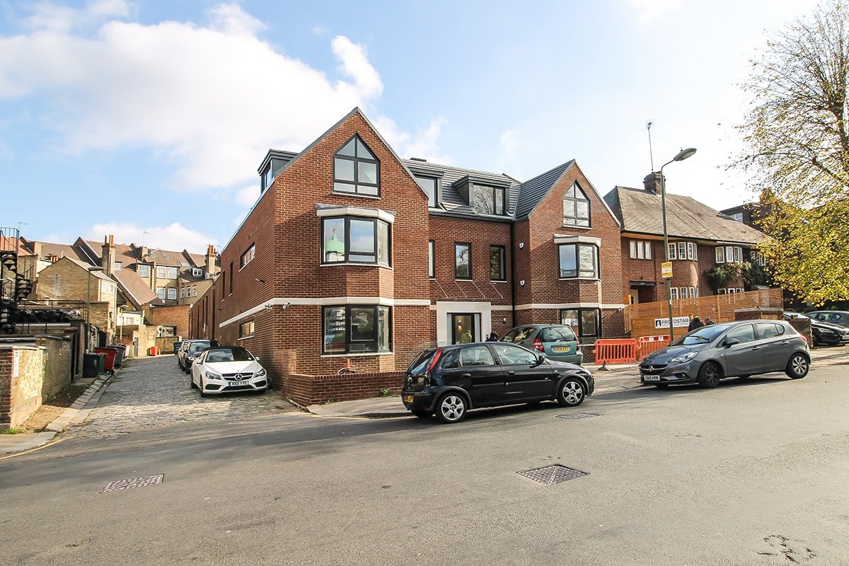 Large red brick building Hodford Road with double fronted bay windows 3-storey on road with cars with black-frame windows