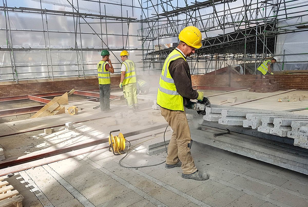 Construction workmen cutting concrete beams on Hodford Road construction site surrounded by scaffolding