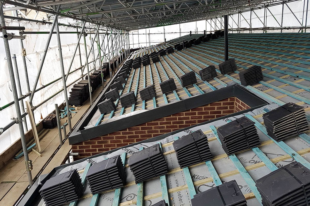 Roof carcass Hodford Road being laid with roofing tiles surrounded by scaffolding