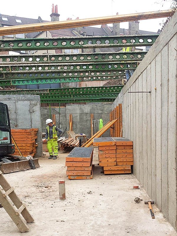 Hodford Road spanning green steel temporary support beams over a new concrete cast in-situ basement with formwork