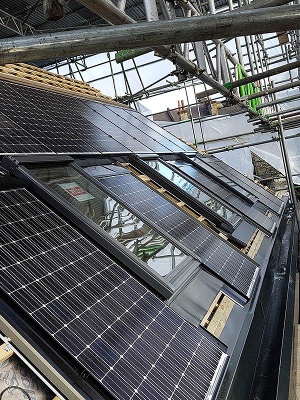 Solar panels fitted on Hodford Road roof adjacent to Velux sky lights surrounded by scaffolding