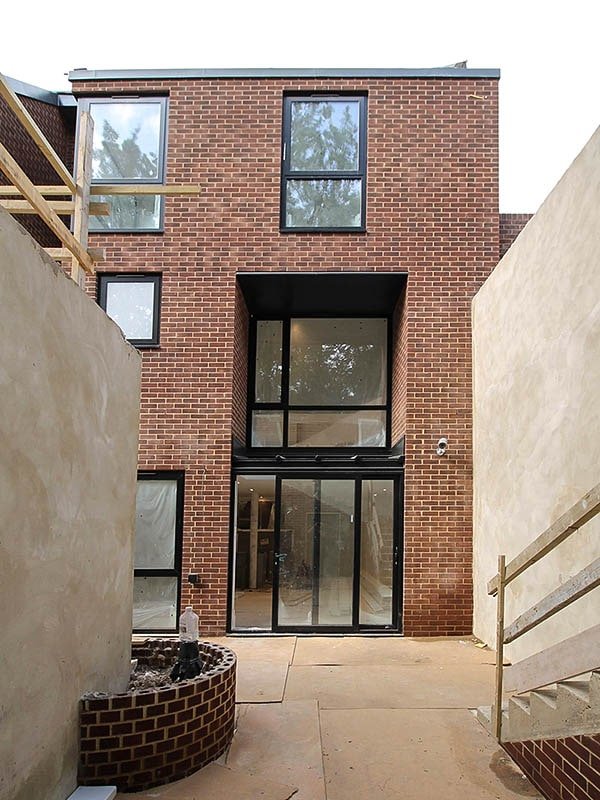 three storey brick buidling Hodford Road under construction showing in-situ cast concrete retaining walls and black windows