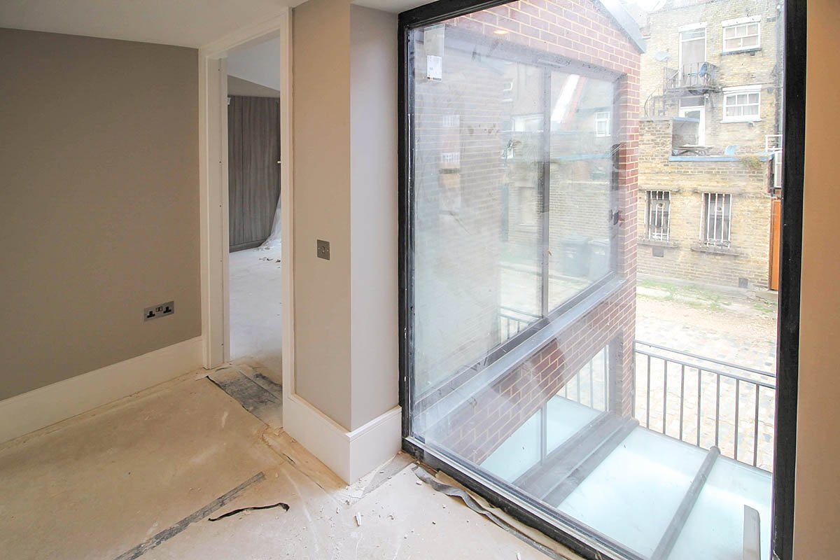 Hodford Road black frame window adjacent to doorway under construction being decorated and sanded