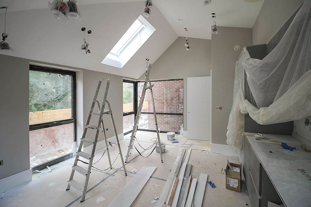 vaulted ceiling room Hodford Road with grey walls undergoing decoration with two windows and skylight and two ladders