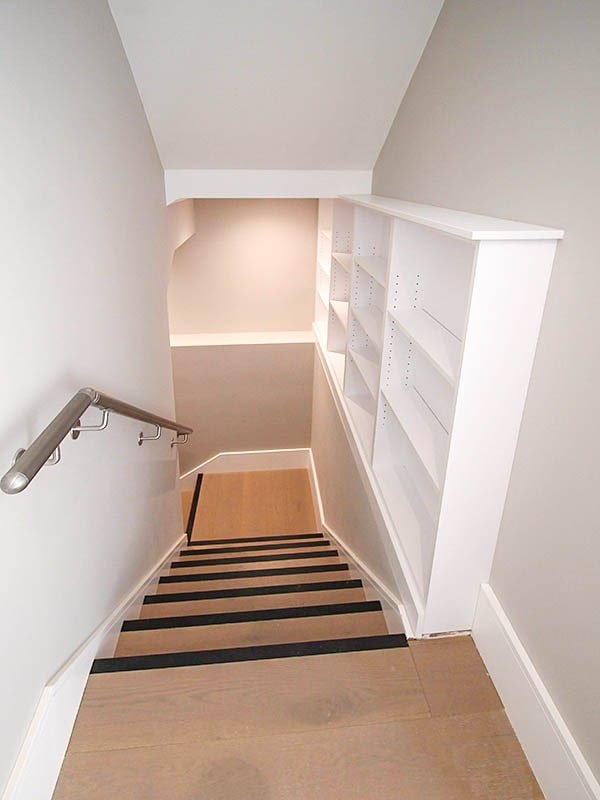 timber communal hallway staircase Hodford Road with metal handrail and bookshelves in white