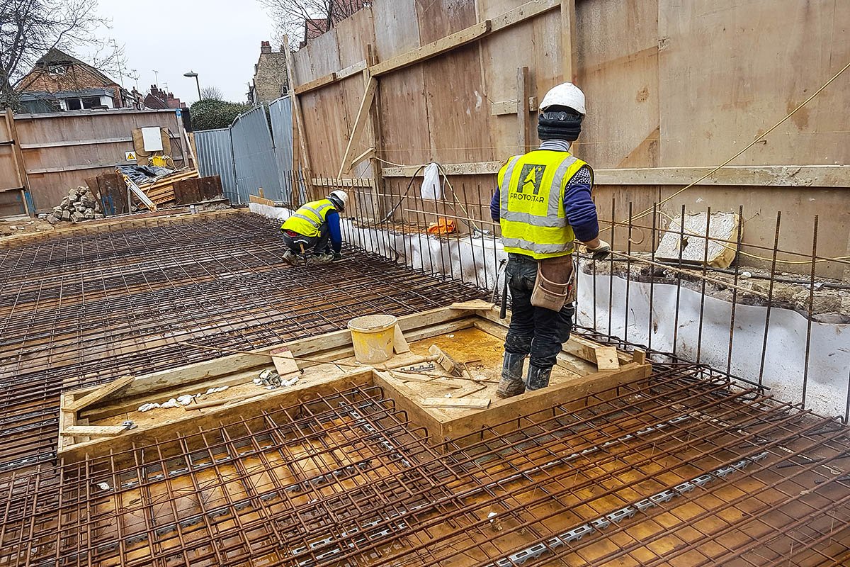 Hodford Road workmen in yellow Protostar high-viz vest working on floor slab steel reinforcement mesh