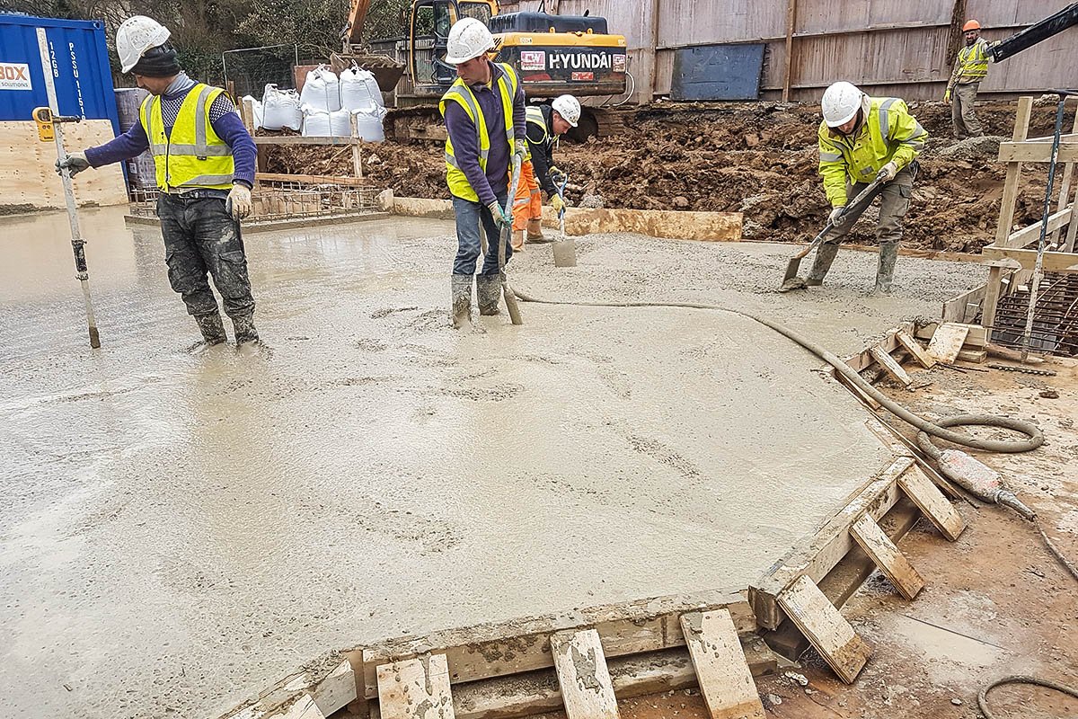 Hodford Road concrete slab being poured and laid by 4 construction workmen in high-viz and white helmets